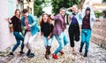 Multicultural friends walking at old town acting crazy funny moves - Happy men and women having fun on city street with party Royalty Free Stock Photo