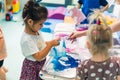 Multicultural group of children milk painting with the teacher helping them, using food coloring for colors. Finger Royalty Free Stock Photo