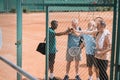 multicultural group of elderly tennis players holding hands together after game