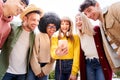 Multicultural group of friends using cell phones and laughing - Cheerful students lined up and looking at Royalty Free Stock Photo