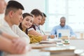 Multicultural group of high school teenage students and teacher at desk with laptop in classroom