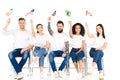 multicultural group of people sitting on chairs with flags of different countries above heads isolated