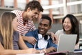 Multicultural group of people working together with a laptop.Young happy friends laughing outside using computer and Royalty Free Stock Photo