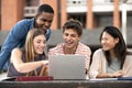 Multicultural group of people working together with a laptop.Young happy friends studying outside using computer and Royalty Free Stock Photo