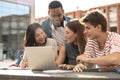 Multicultural group of people working together with a laptop.Young happy friends studying outside using computer and Royalty Free Stock Photo