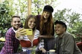 Multicultural happy friends having fun taking group selfie portrait outside in the garden during a coffee break - Mixed race young Royalty Free Stock Photo