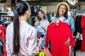 Multicultural hipster girls choosing clothes and using smartphone in boutique Royalty Free Stock Photo