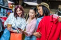 Multicultural hipster girls choosing clothes and using smartphone in boutique Royalty Free Stock Photo