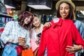 Multicultural hipster girls choosing clothes and using smartphone in boutique Royalty Free Stock Photo