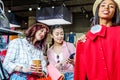 Multicultural hipster girls choosing clothes and using smartphone in boutique Royalty Free Stock Photo