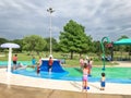 Multicultural kids and parent playing at splash park under summer stormy weather