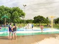 Multicultural kids and parent playing at splash park under summer stormy weather