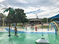 Multicultural kids and parent playing at splash park under summer stormy weather