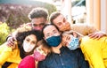 Multicultural milenial friends taking selfie smiling behind face masks - New normal friendship and life style concept Royalty Free Stock Photo