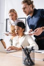 Multicultural office workers looking at laptop