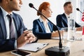 Multicultural politicians sitting near microphones during Royalty Free Stock Photo