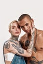 Multicultural relationship. A white pierced woman with tattoos touching a dark-skinned tattooed topless guy standing