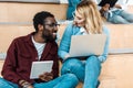 Multicultural students using digital tablet and laptop in lecture hall Royalty Free Stock Photo