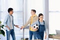 multicultural teenagers showing shrug gestures while friends walking away with football ball Royalty Free Stock Photo