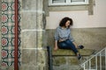 Multicultural woman sitting near the wall of the house in Porto, Royalty Free Stock Photo