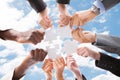 Multiethnic business people assembling jigsaw puzzle against sky Royalty Free Stock Photo