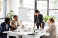 multiethnic businesspeople sitting at tables during conference in office.