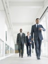 Multiethnic Businesspeople Walking In Office Corridor