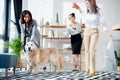 Multiethnic businesswomen fooling around with dog at office