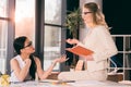 Multiethnic businesswomen in formalwear talking at modern office