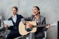 Multiethnic businesswomen playing guitar and using digital tablet