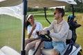 Multiethnic couple taking photos in golf cart and smiling cheerfully Royalty Free Stock Photo
