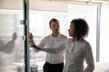 Multiethnic employees draw on glass door cooperating in office Royalty Free Stock Photo