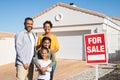 Multiethnic family standing near house sale board Royalty Free Stock Photo