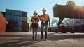 Multiethnic Female Industrial Engineer with Tablet Computer and Male Foreman Worker in Hard Hats and Royalty Free Stock Photo