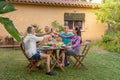 Multiethnic friends toasting happy smiling and laughing in the patio. Middle-aged cheerful people around the table. Royalty Free Stock Photo