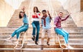 Multiethnic friends walking down stairs with stupid funny moves - Happy guys and girls having fun at urban city center Royalty Free Stock Photo