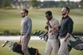 multiethnic golfers holding bags with golf clubs and walking on golf Royalty Free Stock Photo