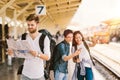 Multiethnic group of backpack travelers using map and smartphone navigation at train station, Asian tourism activity concept Royalty Free Stock Photo