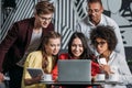 multiethnic group of happy friends lookign at laptop