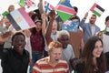 Multiethnic group of happy young peple walking ahead with flags