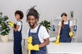 multiethnic group of professional cleaners in rubber gloves smiling at camera while