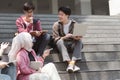 A multiethnic group of university students is studying together while sitting on steps near the campus and communicating Royalty Free Stock Photo