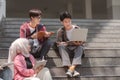 A multiethnic group of university students is studying together while sitting on steps near the campus and communicating Royalty Free Stock Photo