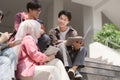 A multiethnic group of university students is studying together while sitting on steps near the campus and communicating Royalty Free Stock Photo