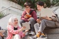 A multiethnic group of university students is studying together while sitting on steps near the campus and communicating Royalty Free Stock Photo