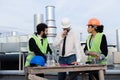 Multiethnic group of workers architect and two engineers have a conversation on the rooftop of building analyzing Royalty Free Stock Photo