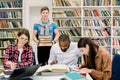 Multiethnic group of young people, students, studying together at the table, reading books. Young boy holding stack of Royalty Free Stock Photo