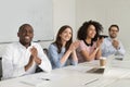 Smiling diverse employees applaud thanking speaker for presentation