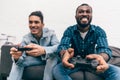 multiethnic male friends with joysticks playing video