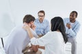 multiethnic mid adult people sitting on chairs and supporting upset man